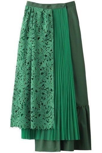 a green skirt is showcased in the image. it is composed of different panels: one is a floral lace panel, the second is a pleated panel, and the third is an asymmetrical panel. the skirt's design is unique with the combination of different textures and styles.