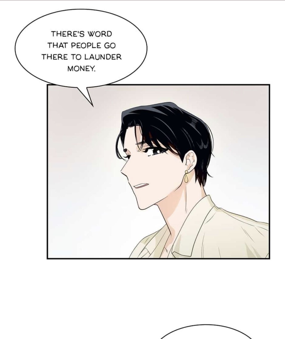 the image is a panel from a manhwa (korean webtoon or comic). it features a closeup side profile of a young man with dark hair and an earring.  he's wearing light beige clothing. a speech bubble above him contains dialogue revealing a rumour that people go to a specific location to launder money. the art style is clean and modern, typical of many manhwas. the overall tone suggests a scene of intrigue or suspicion.