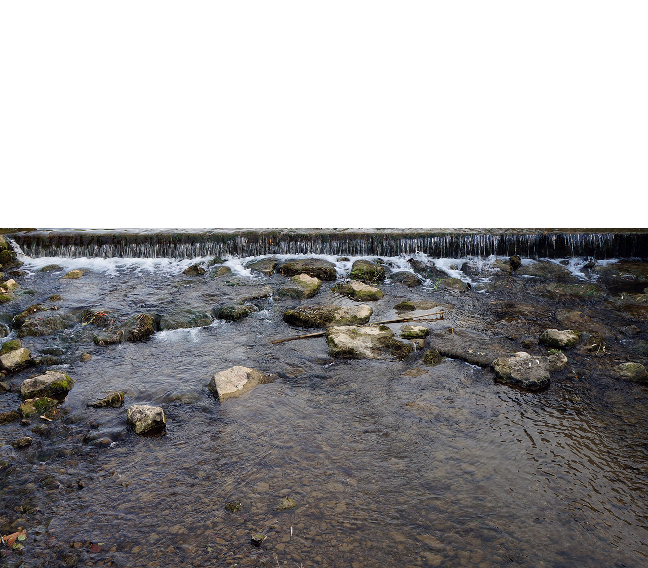 a river flows over rocks and a small dam, creating a waterfall effect in a natural landscape.