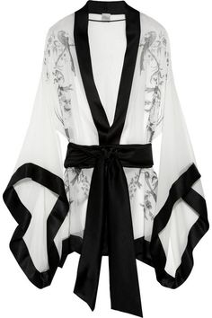 a white silk robe with black satin trim and floral pattern, with a black satin tie belt and black satin cuffs on the sleeves, looks luxurious and elegant. the robe has a delicate and sheer look. it's a stylish piece of clothing that can be worn as sleepwear or lingerie.