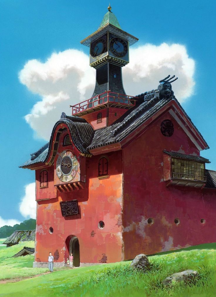 the image is of a tall red clock tower building. two people stand outside the entrance. the building has multiple clocks, and a  black and gray shingled roof. it is surrounded by green grass and a few other buildings are visible in the background. the sky is blue with a few white clouds.