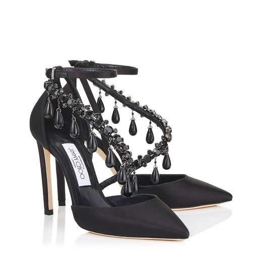 the image shows a pair of jimmy choo black satin pumps.  the shoes are adorned with elaborate crystal embellishments in a teardrop design that extends from the ankle strap down the front of the shoe.  they have a pointed toe and a stiletto heel. the shoes are presented on a white background to showcase their details. one shoe is slightly angled behind the other, giving a good view of both the shoe's side and front profile.
