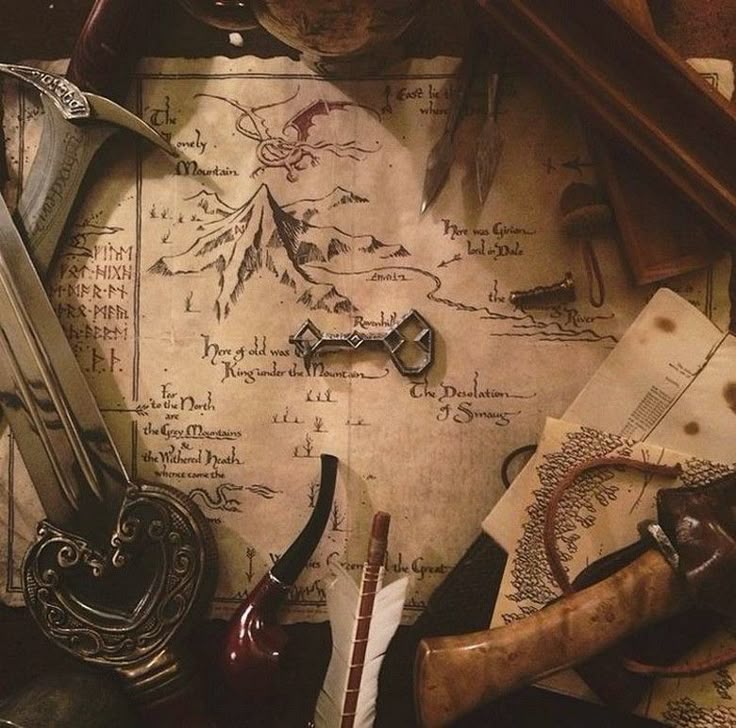 the image shows a detailed map of the lonely mountain from the hobbit, surrounded by various objects. the map includes landmarks like the lonely mountain, smaug, and the desolation of smaug. a silver rivendell key is placed near the mountain. a sword lies on the left side of the map with runes engraved on it. a pipe and an arrow with white feathers are situated in the foreground. the overall scene evokes a sense of adventure and fantasy.