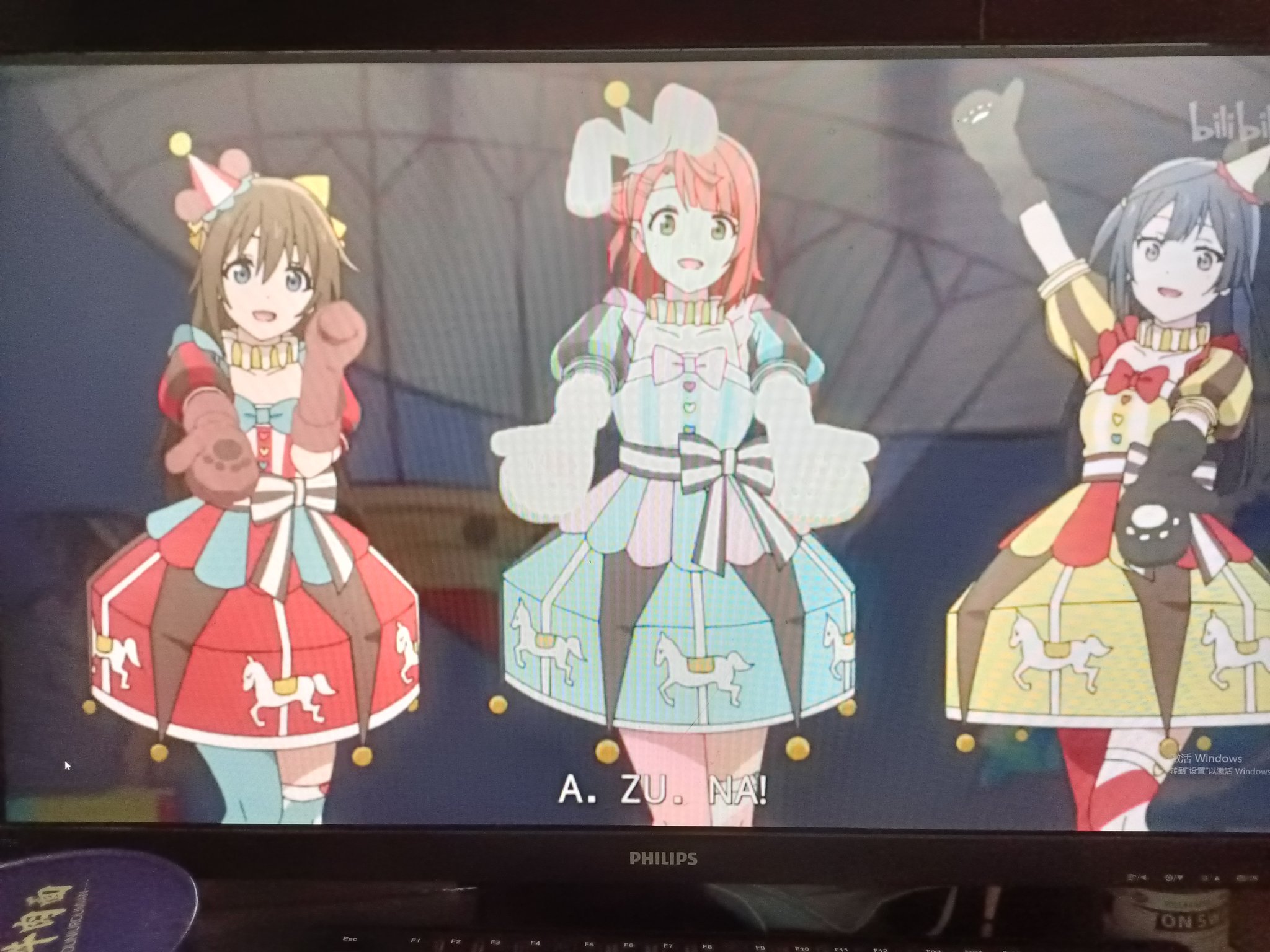 the image shows three anime girls dressed in cute and colorful costumes. they are all smiling and looking happy, suggesting they are performing on a stage. the girls are surrounded by a backdrop of colorful lights and a whimsical setting. the overall vibe of the image is joyful, energetic, and magical.