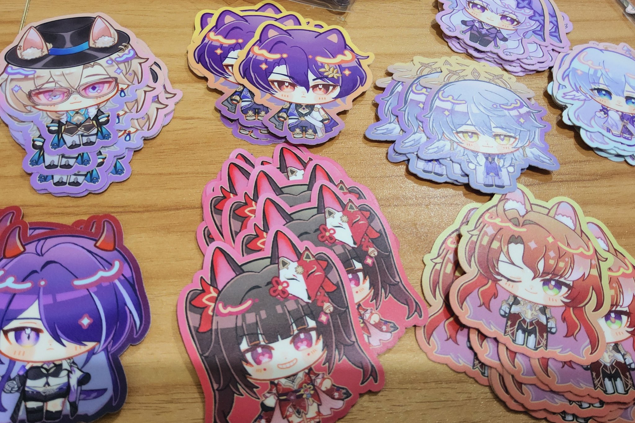 the image showcases a collection of anime character stickers featuring various characters in chibi style. the stickers are arranged on a wooden surface, and they feature a wide range of colors and designs. some of the characters are depicted with cute expressions and accessories, while others have more serious or mischievous looks. the stickers are all incredibly detailed and capture the charm and personalities of the characters they represent.