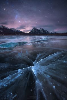 this image showcases a breathtaking winter scene. the foreground features a frozen lake with intricate patterns of ice, illuminated by the celestial glow of the milky way galaxy. in the distance, snowcapped mountains rise against the dark night sky, studded with countless stars. the scene is captivatingly beautiful and serene, encapsulating the magic and grandeur of nature.