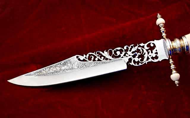 a decorative dagger lies on a red background. the dagger has a silver blade and an ornate white handle with silver and white accents. the blade and handle are intricately detailed with floral and scroll patterns.