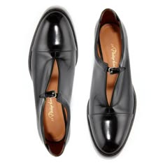 two black leather formal shoes with pointed toes and buckles are displayed on a white background. the shoes are set up as if they were a pair.