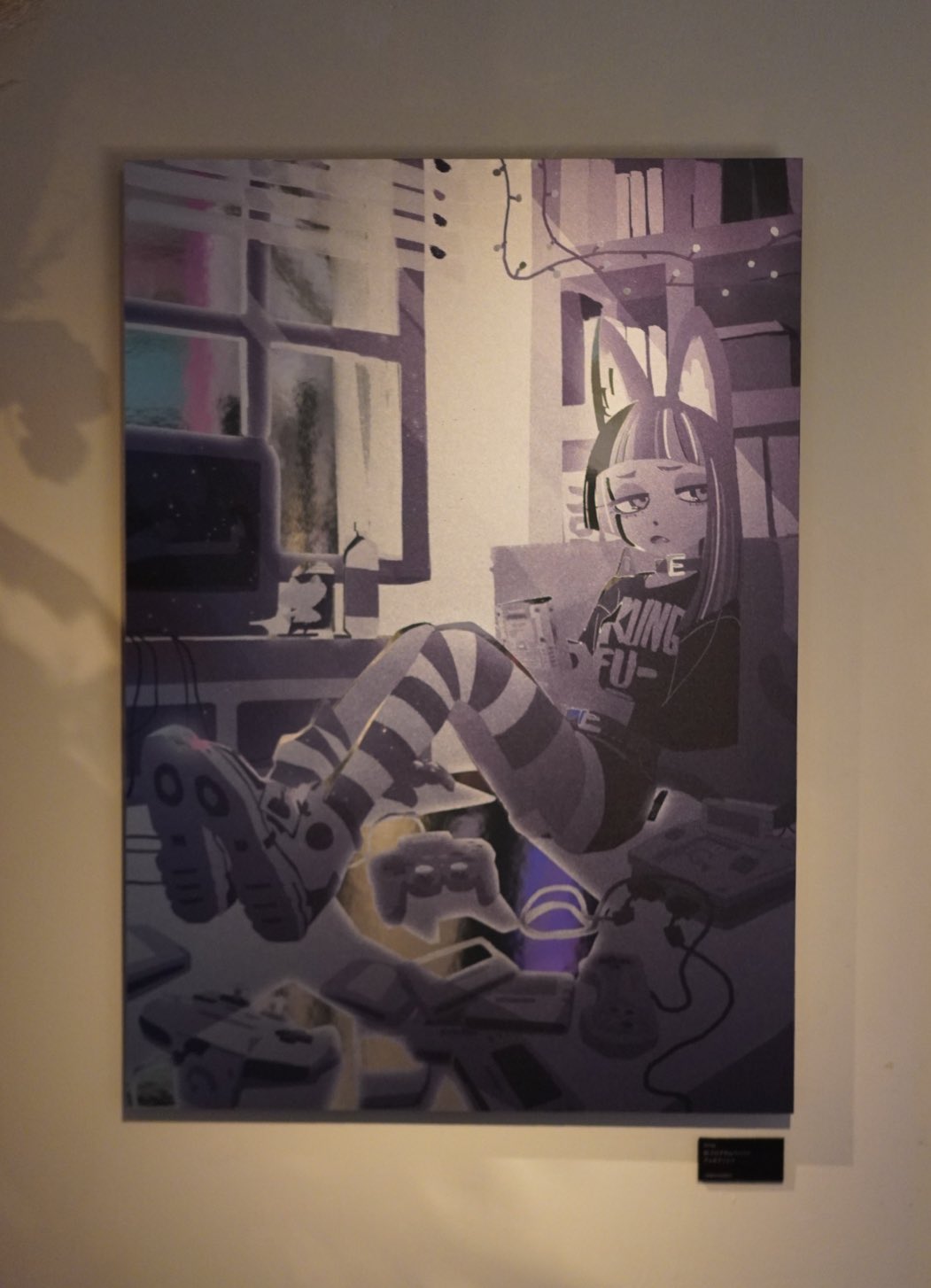 the image showcases a digital illustration of an anime girl in a room filled with retro gaming paraphernalia. the girl, sporting bunny ears and a "king fu" shirt, lounges amidst a collection of vintage gaming consoles and controllers. her relaxed posture and the surrounding technology create an atmosphere of nostalgic gaming culture.