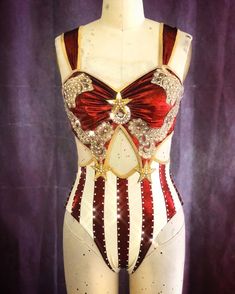 this is a closeup photo of a red and white, starspangled leotard with rhinestone accents. the costume has a sweetheart neckline, thick straps, and a cutout design on the bodice. the bottom portion of the leotard features vertical red and white stripes. the garment is displayed on a mannequin.