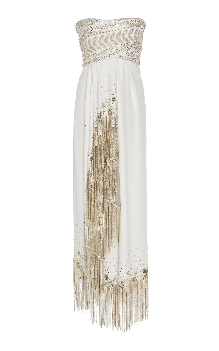a strapless white evening gown with elaborate beaded detailing and a long tassel fringe on one side.