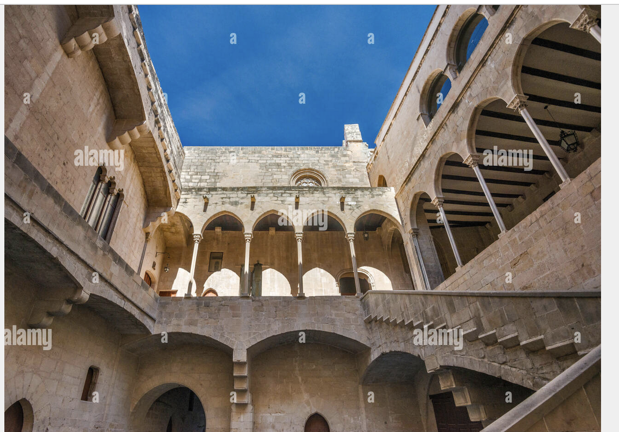 the image showcases the interior courtyard of a historic building with stone architecture, including arches, columns, stairs, and windows, against a blue sky.