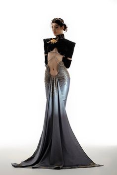 a woman in a long, silver and black gown with a flowing train poses in a studio.