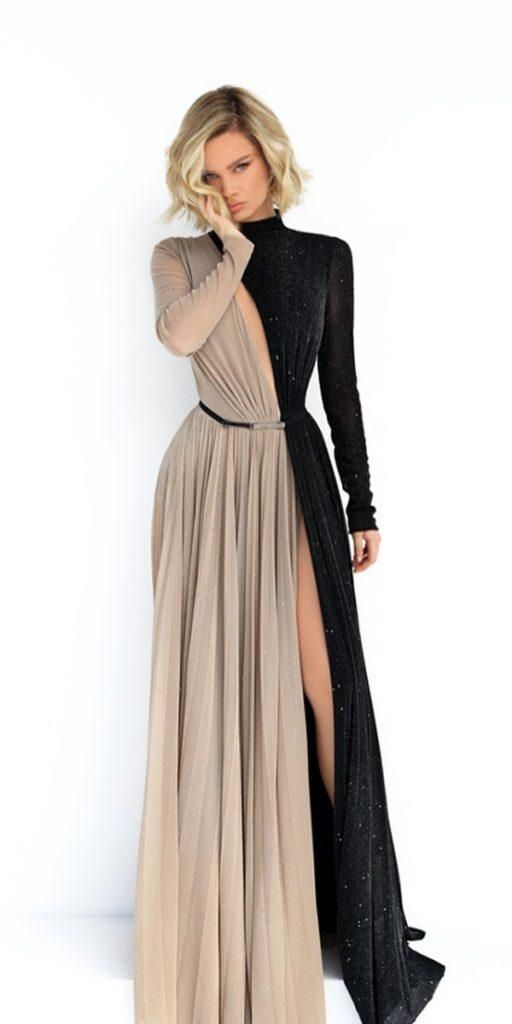 a woman is posing in a long gown that is split down the middle in color and design. the left side of the dress and left sleeve are a tan mesh, and the right side is a black sparkle mesh. the black side has a high slit, revealing the model's leg. the model has blond hair and is looking at the camera with her hand near her face. the background is white.
