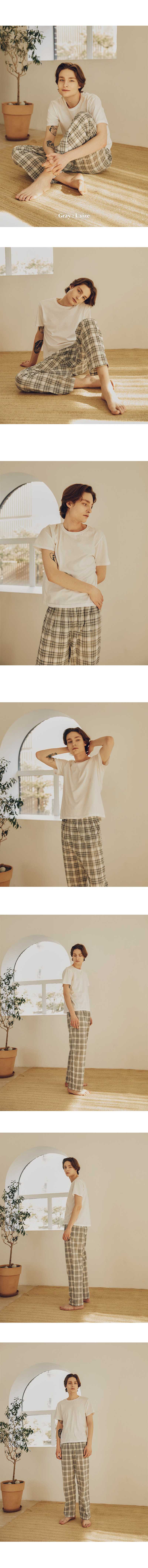 a series of images shows a woman wearing pajamas. in the top image, she is sitting crosslegged on the floor, smiling and holding the bottoms of her pajama pants. the pajama pants are checkered. the top she is wearing is white. a plant sits nearby in a pot. in subsequent images, she is sitting on the floor, standing with her hands behind her head, and standing with her arms at her sides.