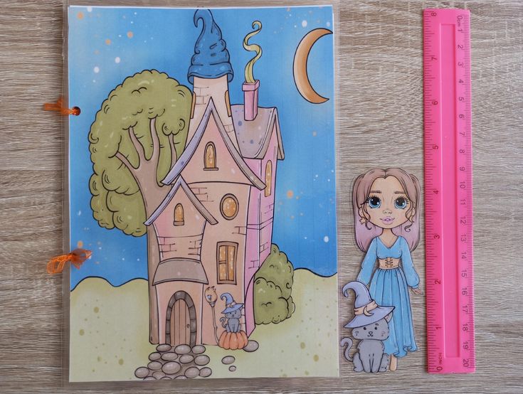 the image shows a drawing of a halloweenthemed castle and a girl with a cat next to a pink ruler on a wooden surface. the castle is pink and has a blue tower and a crescent moon in the background. the girl is wearing a blue dress and has a cat with a witch hat next to her. the pink ruler is used as a scale to measure the sizes of the drawings.