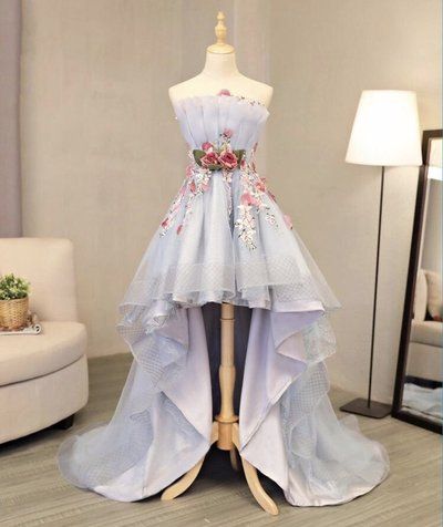 a light blue strapless dress on a mannequin with floral embroidery. the dress is highlow and made of tulle. the dress is photographed indoors in a welllit room.