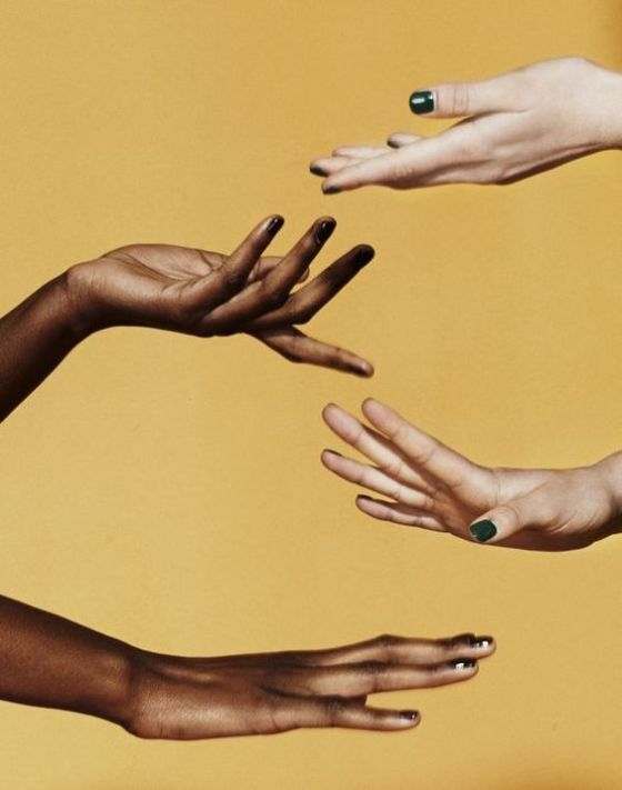 three hands reach out towards each other, their fingertips almost touching. two of the hands belong to people with darker skin tones, while the third hand belongs to a person with lighter skin. they are reaching towards each other in a gesture of connection and unity. the hands are the focus of the image, and the yellow background is a simple, yet effective backdrop. the image is a powerful visual representation of diversity and inclusion.