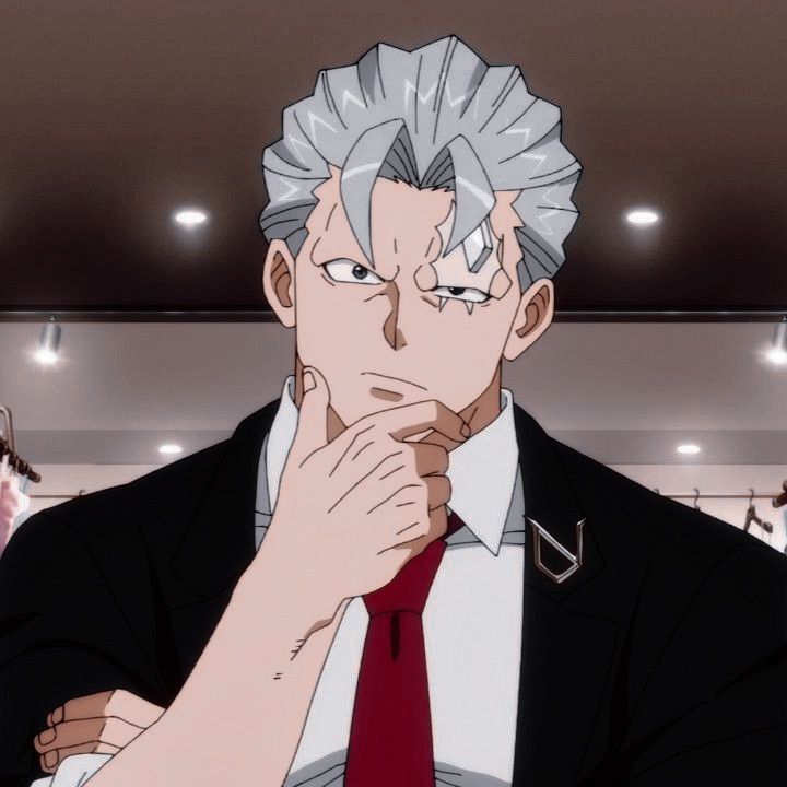 the image features a portrait of an adult male anime character with short, spiky gray hair and a scar over his left eye. he wears a black business suit with a crisp white shirt and a red tie.  he is posed with his right hand thoughtfully on his chin, his expression serious. the background suggests an indoor setting, possibly a store, with blurred clothing racks and overhead lighting.