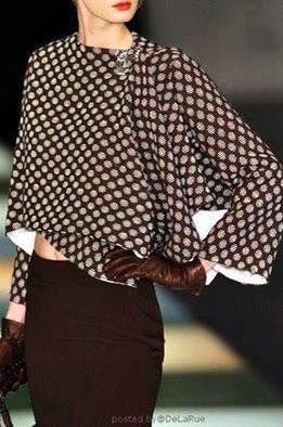 a woman in a brown and white polka dot top and a matching brown skirt stands with her hand on her hip, wearing long brown gloves, looking elegant and chic. the outfit is very stylish and trendy.