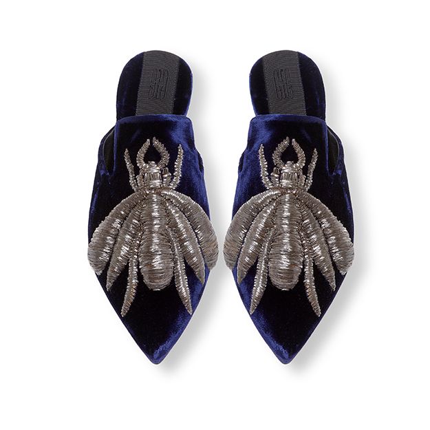 a pair of pointedtoe, blue velvet mules with silver embroidery in the shape of an insect, likely a bee. the shoes are seen from above.