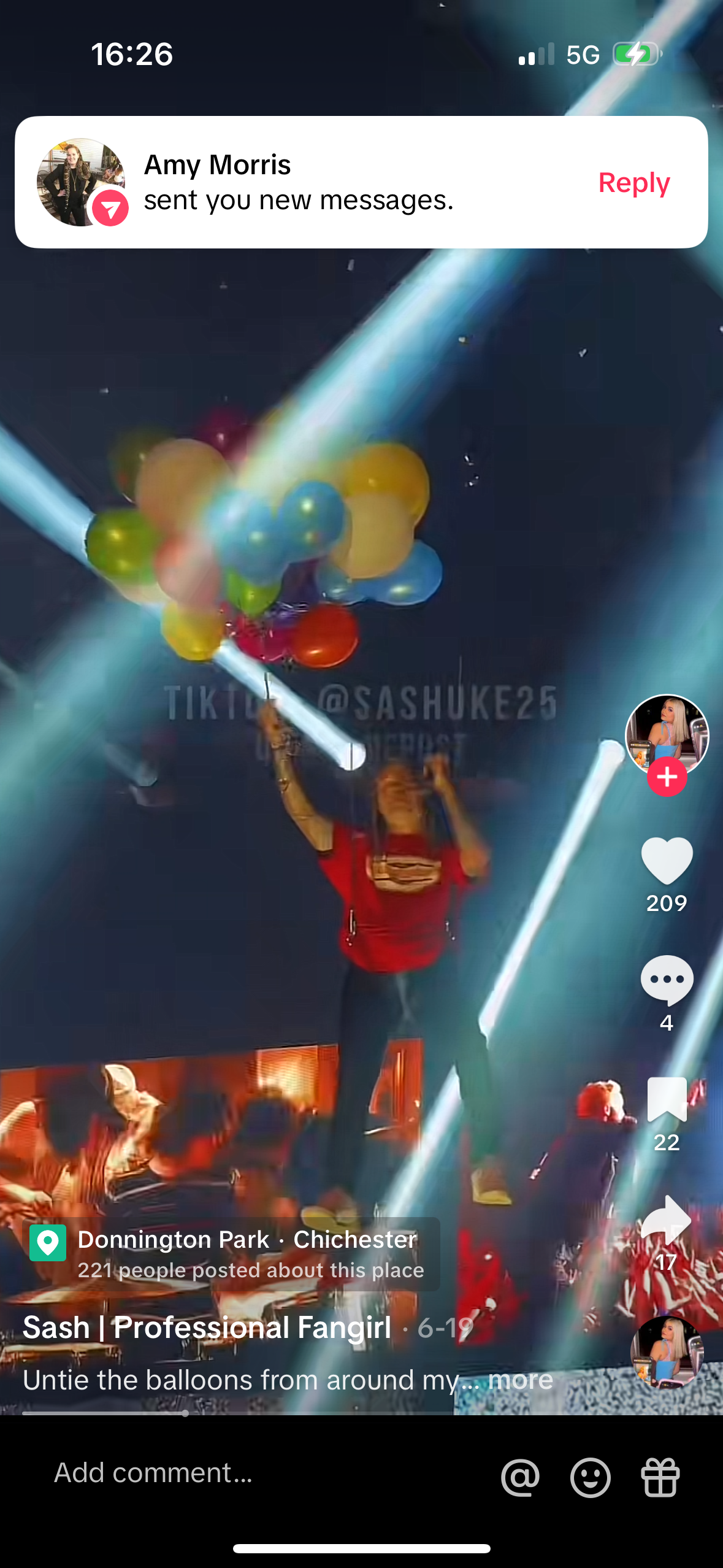 a screen capture of a tiktok video of a girl wearing a red shirt trying to untie a bunch of balloons from around her neck, with a message at the top that says "amy morris sent you a new message." the person in the video has a tiktok profile name "@sashuke25" and has 209 likes and 4 comments on her video. the user is filming at donnington park, chichester.