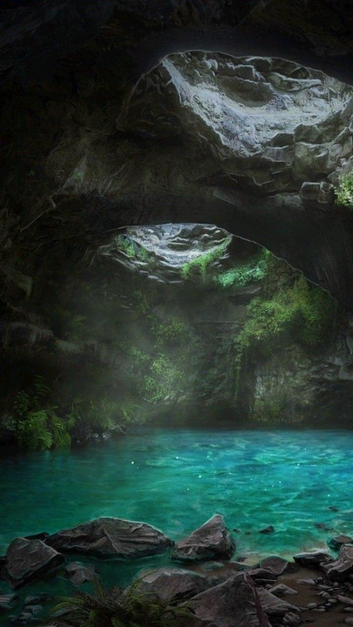 the image showcases a picturesque scene inside a cave, featuring turquoise blue water. sunlight filters in through an opening, creating a magical ambiance. the rocky walls of the cave are adorned with lush green vegetation, and mist adds to the ethereal atmosphere. boulders and rocks are scattered near the water's edge.