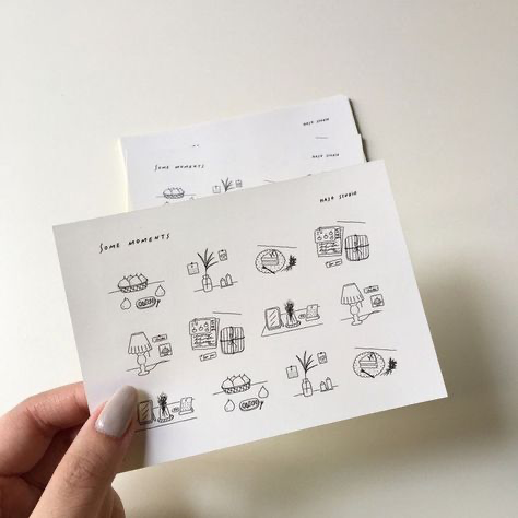 a hand is holding a sheet of paper with black and white drawings of home decor and interior items on it. the paper is titled "some moments" and "make space".  the drawings are minimal and cute, and they create a warm and inviting atmosphere.