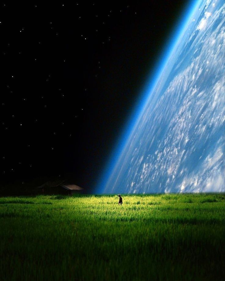 a person stands in a green field near a house, with a view of earth and the starry sky in the background. the earth takes up a large portion of the right side of the image.
