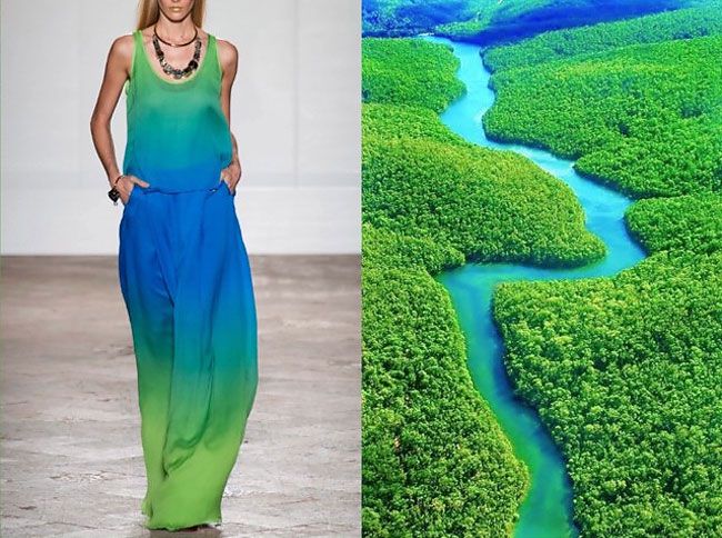 a woman wearing a long, ombre dress in shades of green and blue walks the runway, while on the right side of the image, an aerial view of a river winding through a lush green jungle is shown. the two images are separated by a vertical line. the woman's dress is reminiscent of the colors and shape of the river, creating a visual connection between the two scenes. the juxtaposition of the woman's fashion and the natural landscape highlights the beauty of both.