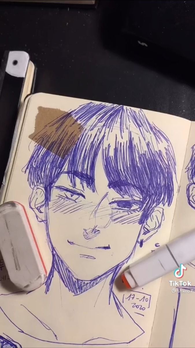 the image shows a closeup view of a sketchbook page with a detailed ink drawing of an animestyle boy's face. the drawing is predominantly done in shades of purple ink, with fine lines creating texture in the hair and facial features.  the boy has short, dark hair and a soft expression.  in the lower right corner, a white marker and a small eraser are visible, suggesting the drawing is in progress.  there's also a date written on the page, "17102020."  a piece of tape is partially visible on the drawing, suggesting it may have been previously altered or worked on. the background includes the edge of a black surface and a small portion of what appears to be a notepad or other paper items. the overall aesthetic is casual and artistic.