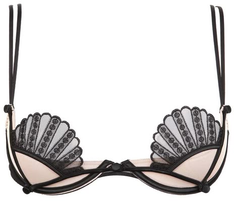 a closeup shot of a pale pink halfcup bra with black lace accents in the shape of fans on each cup. the bra has black straps and a black band underneath the cups. the overall design gives a sensual and vintage aesthetic.