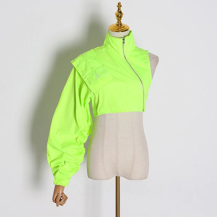 a neon green cropped jacket with a oneshoulder design. the jacket has a zipper closure and a ruched sleeve.