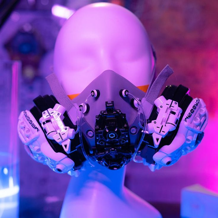 the image showcases a futuristic gas mask fitted onto a featureless, purplehued mannequin head. the mask, primarily black and white, boasts a complex design with visible tubes, filters, and potential technological components. the backdrop is a vibrant, neonlit space awash in purple, blue, and pink hues, contributing to a cyberpunk or dystopian aesthetic.