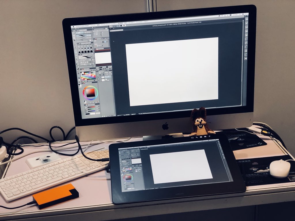 the image shows a desktop computer setup for digital art or graphic design. it includes an apple imac computer with a large display, a wacom drawing tablet, a keyboard, and a mouse. the workspace is welllit and appears to be in an office or studio setting.