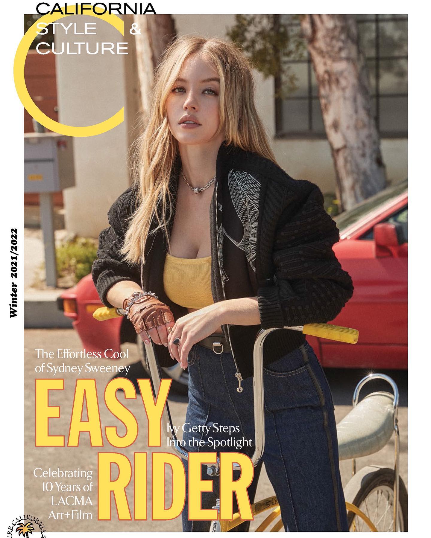 the image is a magazine cover featuring sydney sweeney, an actress, leaning on a vintagestyle bicycle. the cover's design is evocative of 1970s california style, incorporating warm colors and retro elements. the text highlights a celebration of lacma's 10th anniversary of art + film and also mentions ivy getty.  sweeney is dressed in a dark jacket, a yellow top, and blue jeans. the background features a classic car and a setting that hints at a southern california atmosphere. the overall tone suggests a blend of fashion, culture, and artistic celebration.