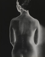 the image is a black and white photograph of a nude female figure viewed from behind. the subject's back and shoulders are prominently displayed, with the body softly illuminated against a dark background.  the lighting and focus create a sense of both intimacy and abstraction, emphasizing the forms and curves of the body. the overall style suggests a classic or vintage fine art photograph. the photograph's mood is quiet and contemplative.