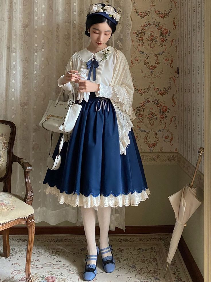a young woman stands gracefully in a vintageinspired room, showcasing a classic lolita fashion outfit. she wears a navy blue skirt with delicate lace trim, paired with a white blouse featuring a charming peter pan collar. a creamcolored shawl with lace detailing adds an extra touch of elegance. her accessories include a white handbag, a floral adorned hat, and blue mary jane shoes.  the setting complements her attire, with its floral wallpaper, lace curtains, and an antiquestyle chair. the bright, natural light enhances the overall romantic and feminine aesthetic.