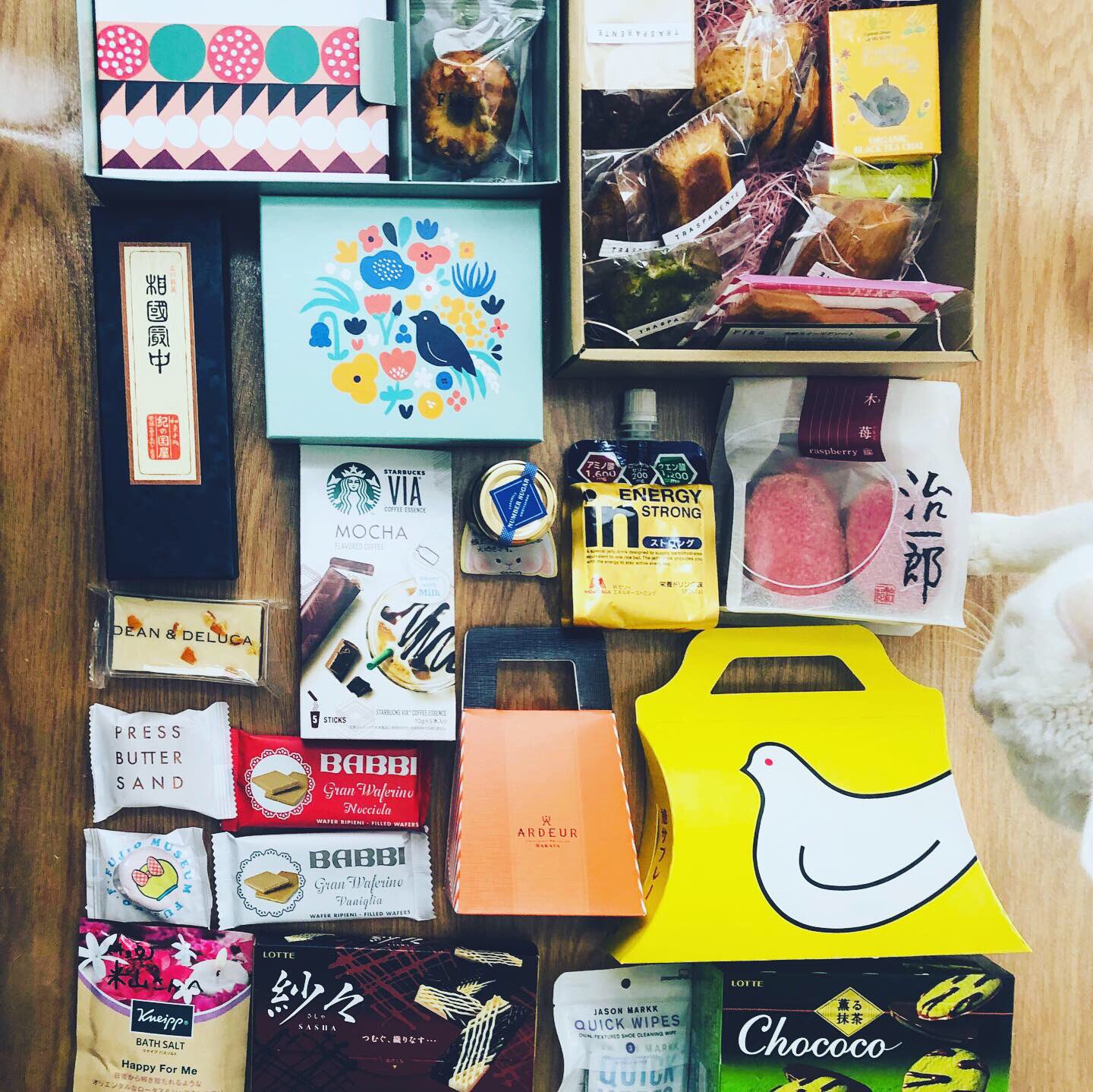 a flat lay of an assortment of japanese snacks and treats, arranged on a wooden surface. the image showcases a delightful variety of packaging, colors, and types of sweets, hinting at a delightful culinary experience.
