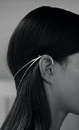 close up shot of a woman wearing a silver headpiece that wraps around her ear. the image is in black and white.