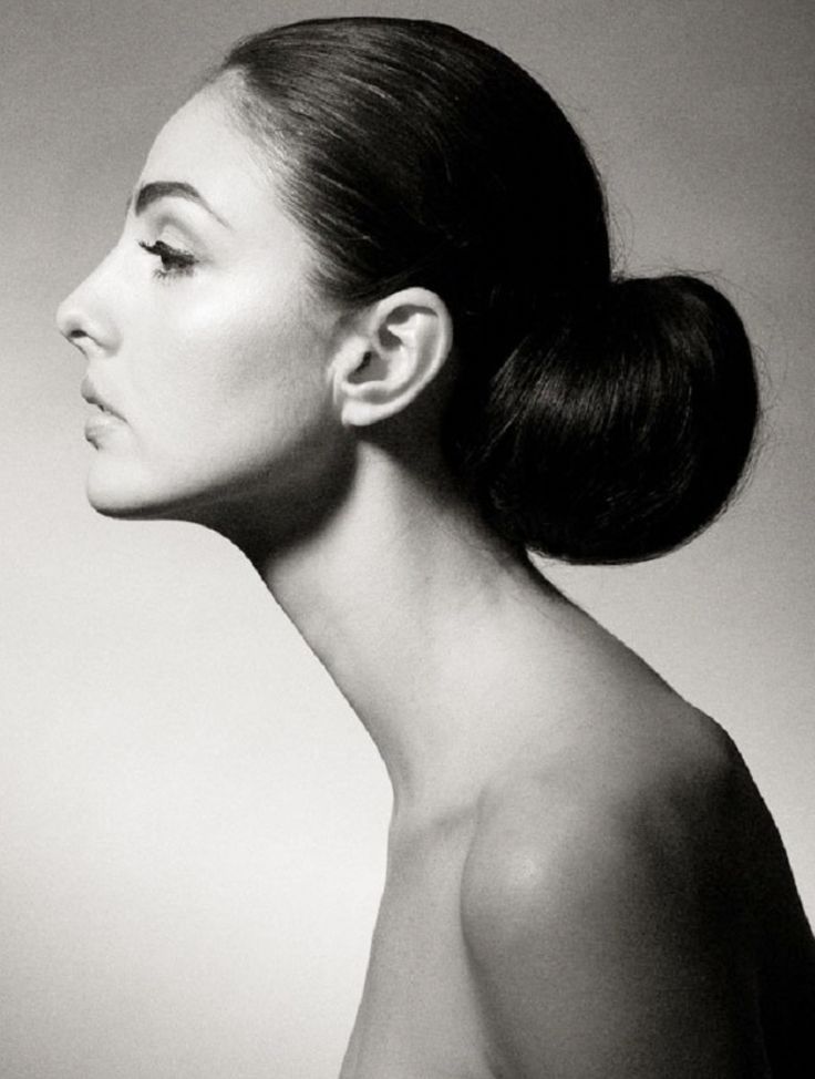 a black and white portrait of a woman in side profile. she has her hair pulled back in a neat bun and a long, elegant neck. the image focuses on her face, neck, and shoulder, with a classic and timeless feel.