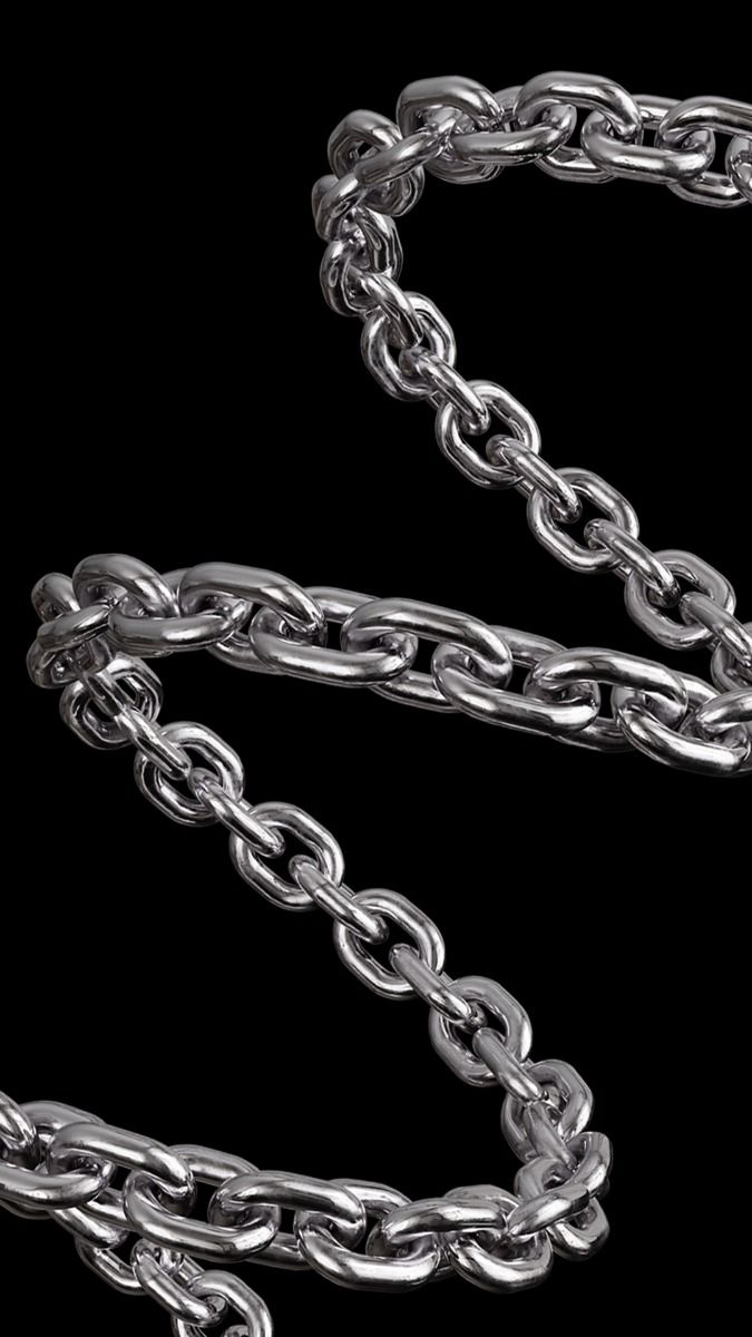 a thick silver chain is laid out in an s shape against a black background. the metal is reflective and shows the light source.