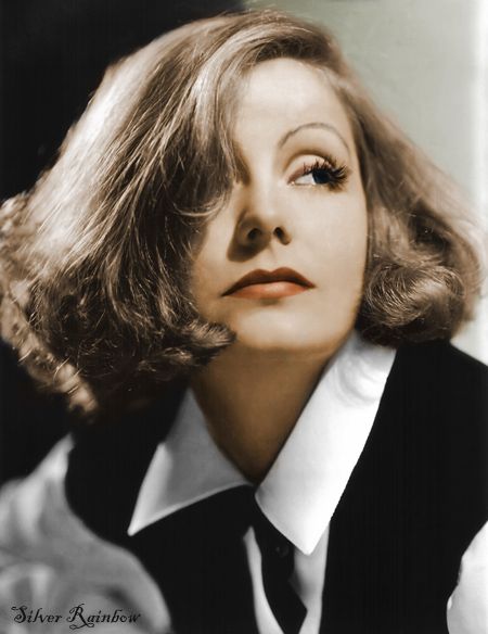 a portrait of a woman in a black and white outfit with her hair styled in loose waves. she is looking to the side with a serious expression on her face. the woman is wearing a white blouse with a black vest. her hair is parted on the side and styled in loose waves.  she is looking off to the side with a serious expression on her face.  the lighting is soft and creates a classic, glamorous look.