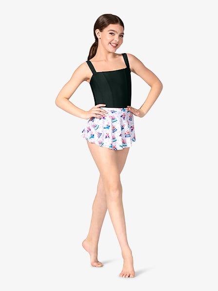 a fulllength photograph shows a young girl, possibly a dancer, smiling confidently. she is wearing a black leotard and a short, white tutustyle skirt decorated with a colorful birthday cake print.  her hair is pulled back, and she is barefoot. the background is plain white, focusing attention on the girl and her outfit. she appears to be in a dance studio or similar setting, showcasing her dance attire.  her pose and expression suggest selfassurance and readiness.