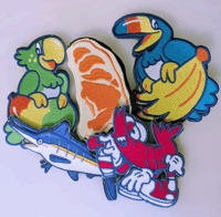 the image shows a collection of brightly colored, embroidered patches featuring various cartoon characters and food items.  the patches appear to be designed in a whimsical, possibly retro style.  specific characters/items include a toucan holding a banana, a parrot holding a mangolike fruit, a marlin fish, a shrimp character in sneakers, and a slice of salmon.  the patches are piled loosely together, showcasing their unique designs and vibrant colors. they are likely intended for sewing or ironing onto clothing or other fabric items.
