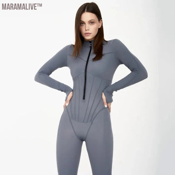 a woman poses in a formfitting, gray athletic bodysuit. the bodysuit features long sleeves, a high neck with a zipper, and a corsetstyle bodice with vertical seams. the lighting is soft and the background is a light gray, creating a clean and minimalist aesthetic.  the image focuses on showcasing the design and fit of the garment.