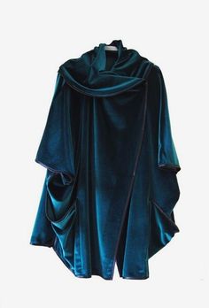 a closeup view of a teal velvet shawl with a draped collar. the shawl is draped and flowing, giving it a luxurious and elegant look. the shawl is made of soft velvet fabric and has a unique design that makes it both fashionable and stylish. it is a perfect garment for layering and adding a touch of elegance to any outfit.
