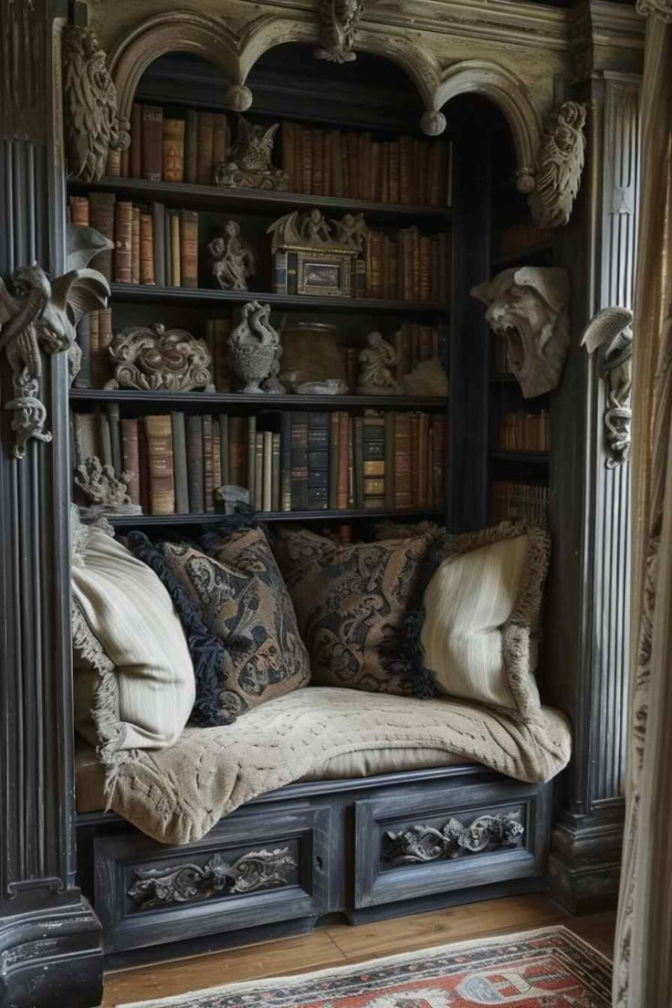 the image shows a gothicstyle reading nook built into a bookshelf. the bookshelf is filled with books and various ornate statues and carvings, including gargoyles. a comfortable cushion and several pillows are placed in the nook, inviting someone to sit and read. below the nook are drawers with carved details. the architecture and design are classical and ornate.