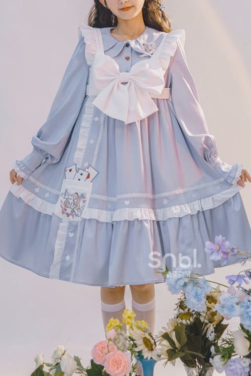 a young woman models a charming light blue lolita fashion dress. the dress features a white peter pan collar, a large white bow tied at the chest, and layers of delicate white frills along the hemline and sleeves. playful embroidered details, including playing cards and hearts, adorn the skirt. the dress falls to just above the knee, showcasing white stockings and the suggestion of mary jane shoes. the backdrop is a soft white, accented by a vibrant bouquet of flowers in pink, yellow, and blue hues at the bottom right corner, complementing the dress's color scheme. the image exudes a sweet and youthful energy.