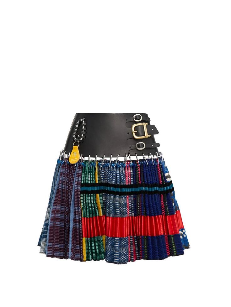 a closeup shot of a colorful, multilayered, pleated skirt. the skirt features a black leather waistband with silver chain and gold buckles and loops. the skirt is made of a variety of fabrics and is pleated in a variety of ways, giving it a unique and stylish look. the skirt is a great option for a variety of occasions, from casual to formal. it can be dressed up or down depending on the occasion.